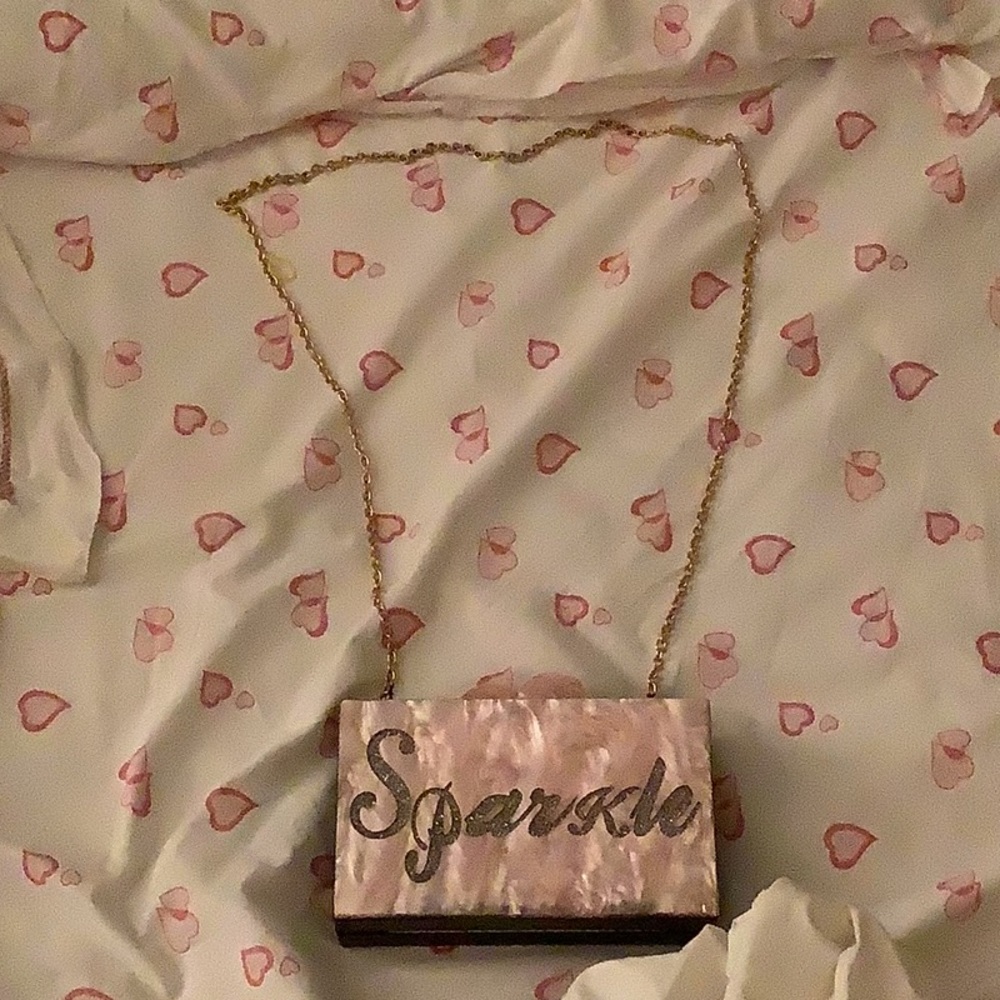 A pink glittery purse with gold chain.